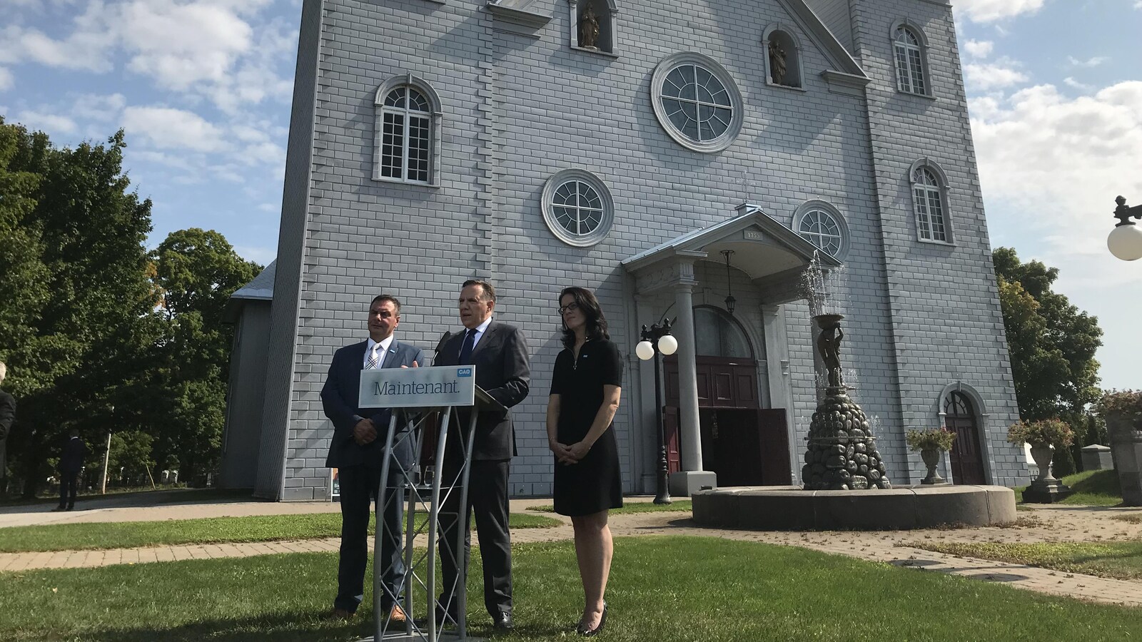 François Legault est en point de presse devant une église de Québec avec Sonia Lebel et un candidat local.