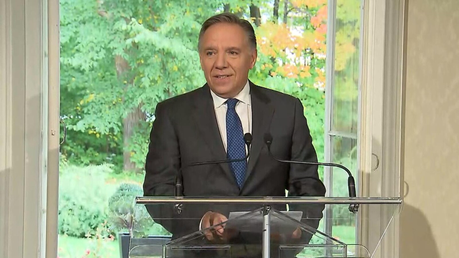 François Legault au podium, devant une fenêtre.