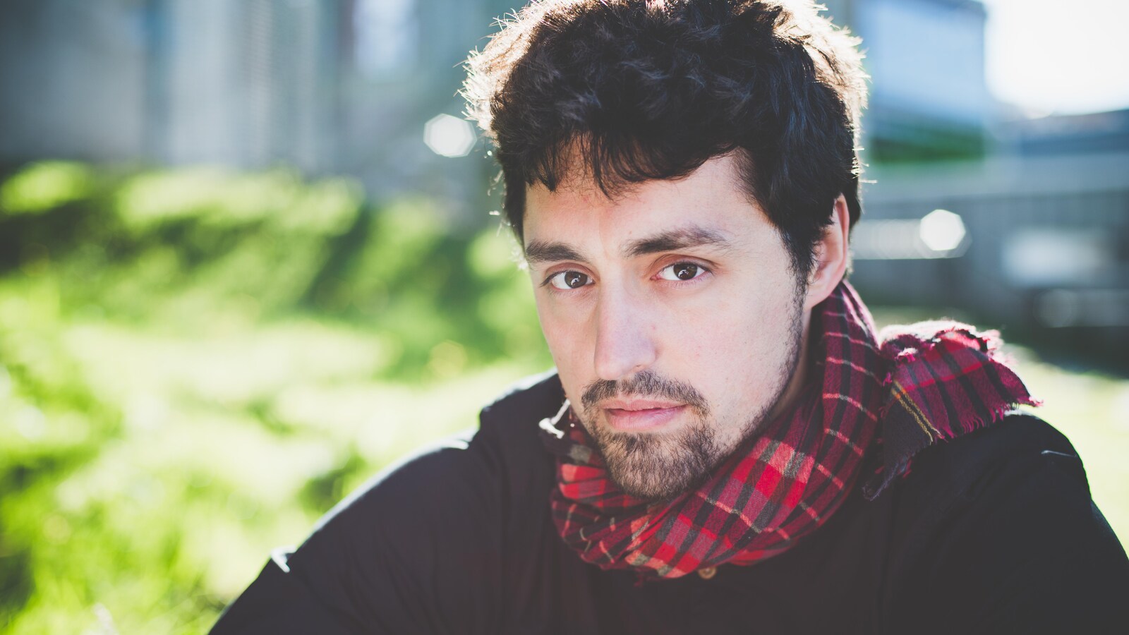 Portrait en couleur de Frédérick Lavoie. Il porte un chandail noir et un foulard à carreaux rouges.