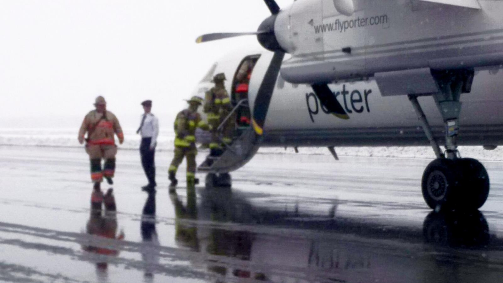 Trois pompiers montent dans l'avion immobile sur le tarmac