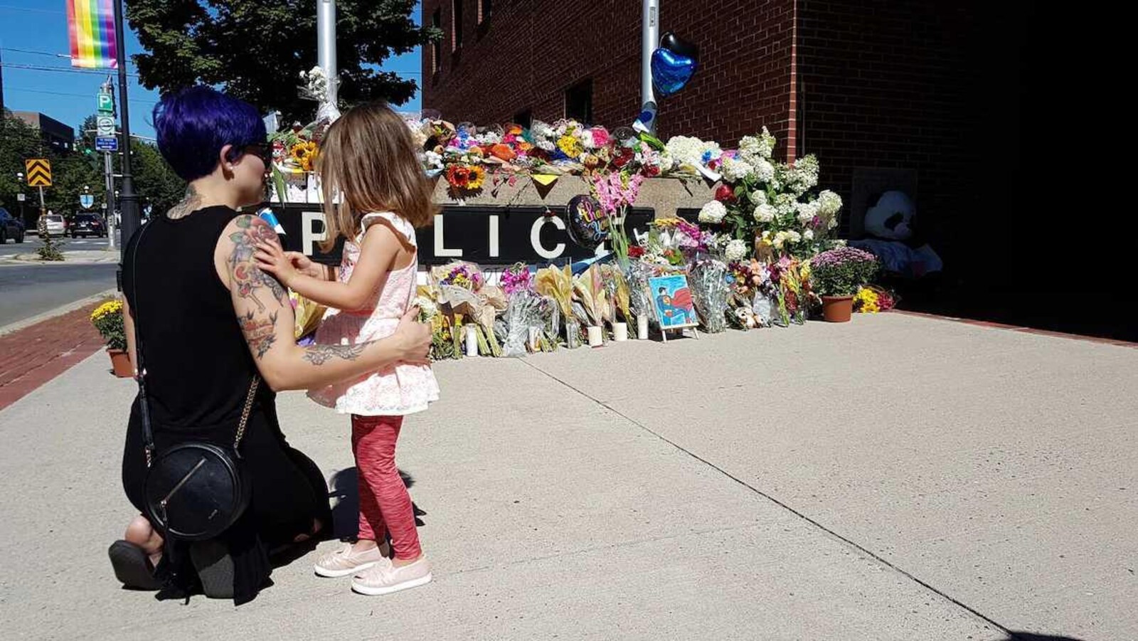 Une femme et une fillette observent un mémorial devant un poste de police à Fredericton le 11 août 2018.