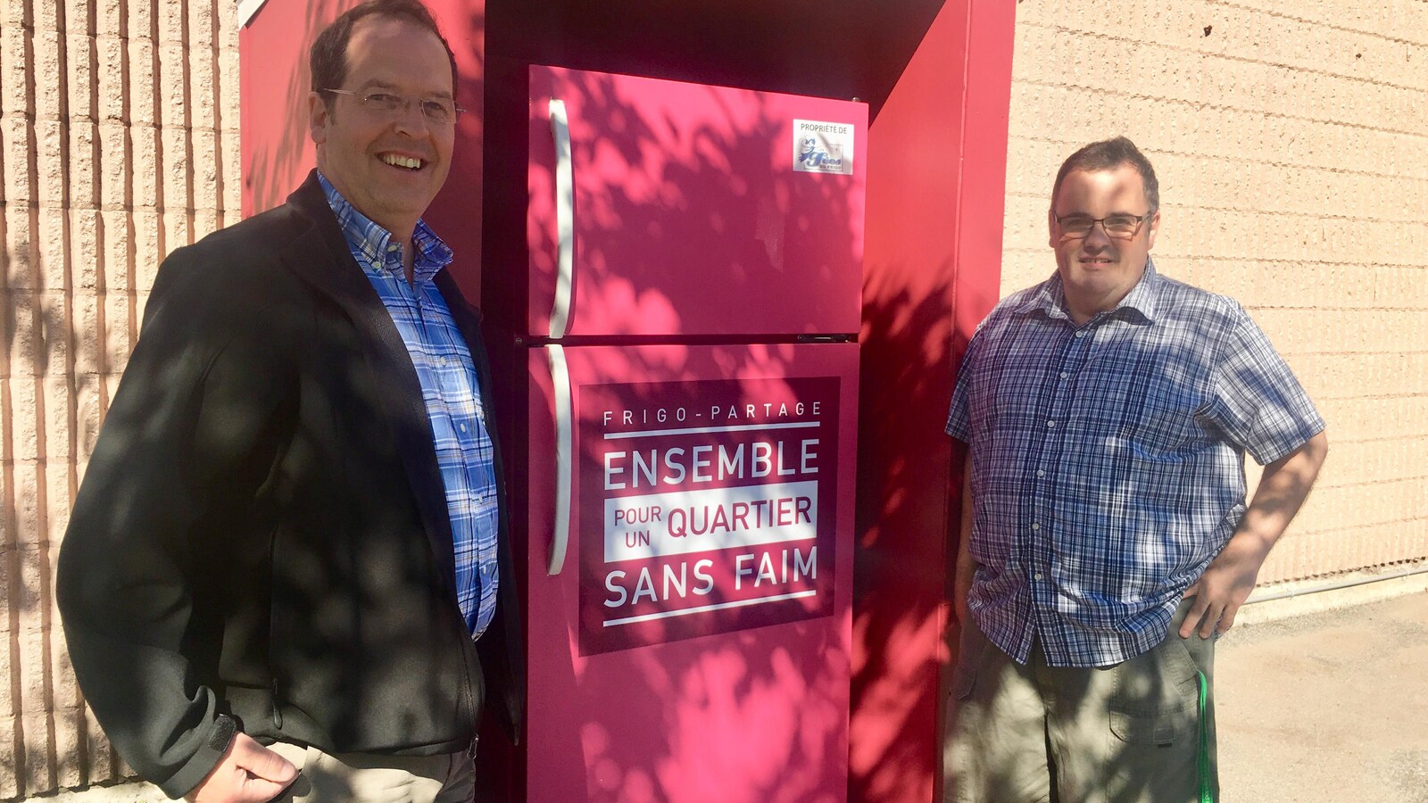 Martin Deschênes, directeur du Service d'entraide du Patro Roc-Amadour, et Mario Hébert, animateur Service d'entraide du Patro Roc-Amadour, posent devant le frigo-partage.