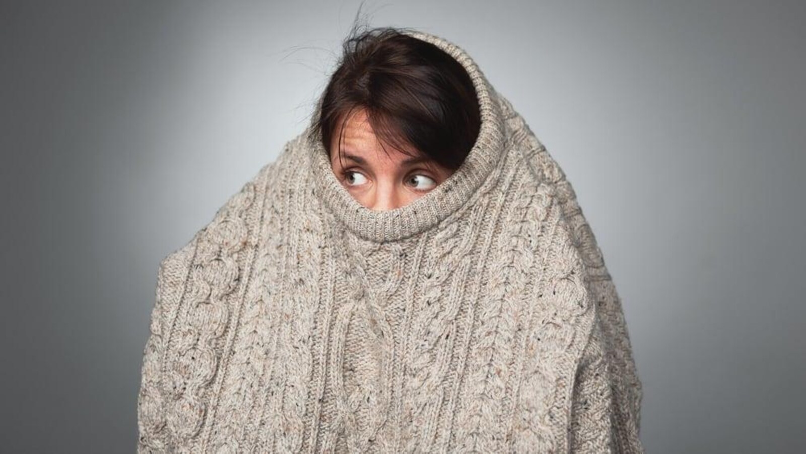 Une femme a le nez recouvert et une partie de la tête sous son chandail.