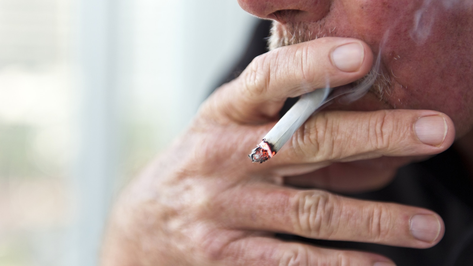 Un homme fume une cigarette.