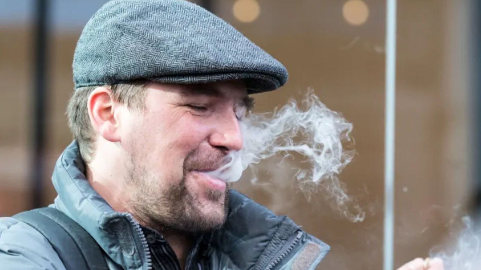 De la fumée s'échappe de la bouche d'un homme.