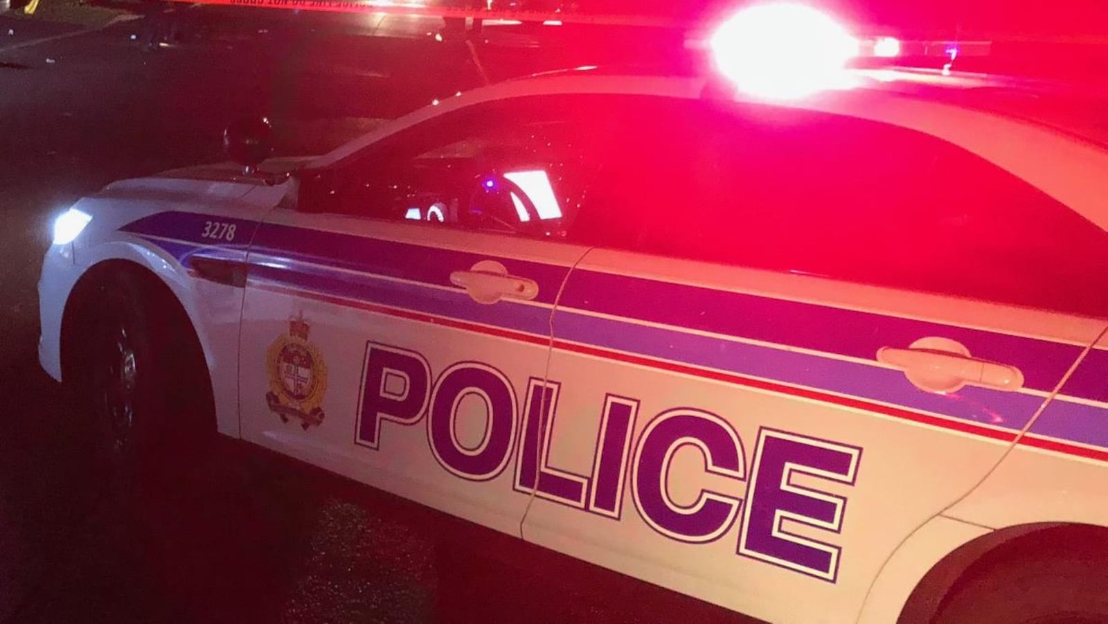Des voitures de police avec les gyrophares allumés devant un périmètre de sécurité
