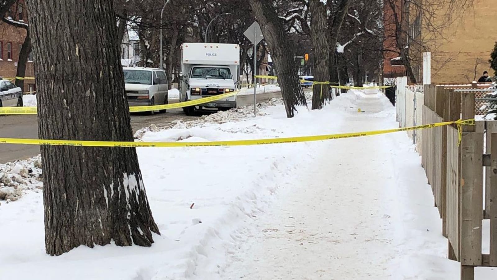 Du ruban jaune de la police entoure un terrain sur une rue enneigée.