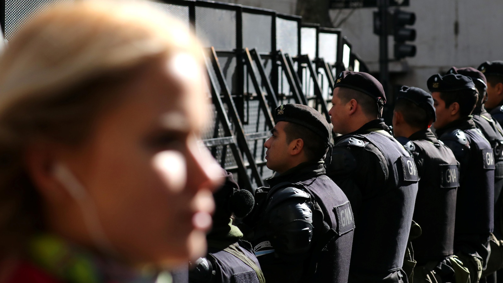Une femme marche devant des policiers antiémeute.