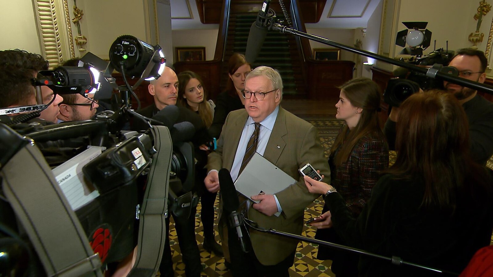 Gaétan Barrette est entouré de journalistes avec leurs micros et leurs caméras.