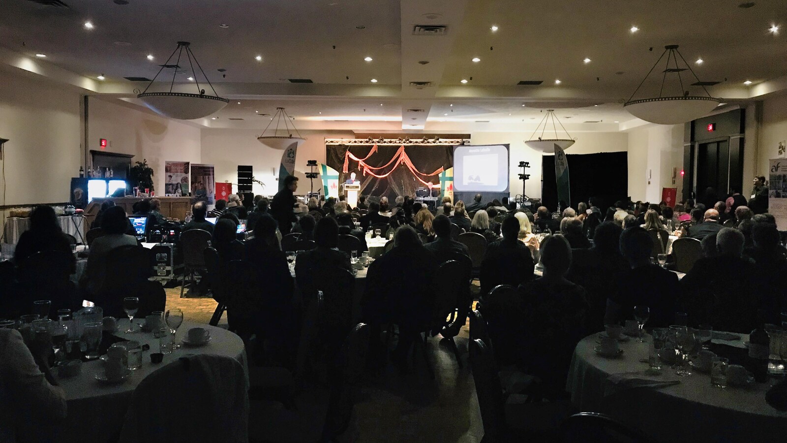 Assis devant une scène, des gens assistent au Gala de la Fransasque.