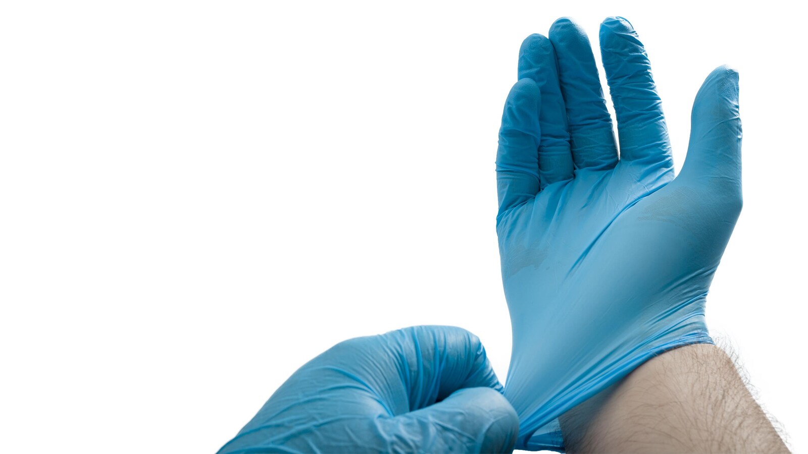 Un homme enfile des gants chirurgicaux bleus.
