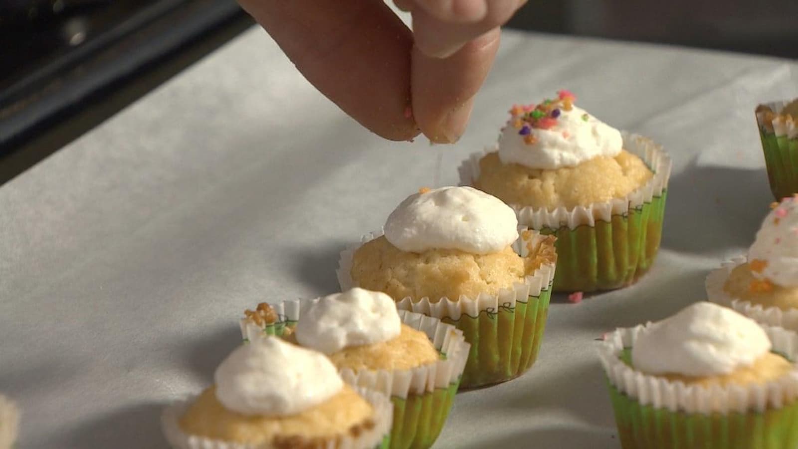 Mme Guimond met un glaçage à la vanille sur ses petits gâteaux.