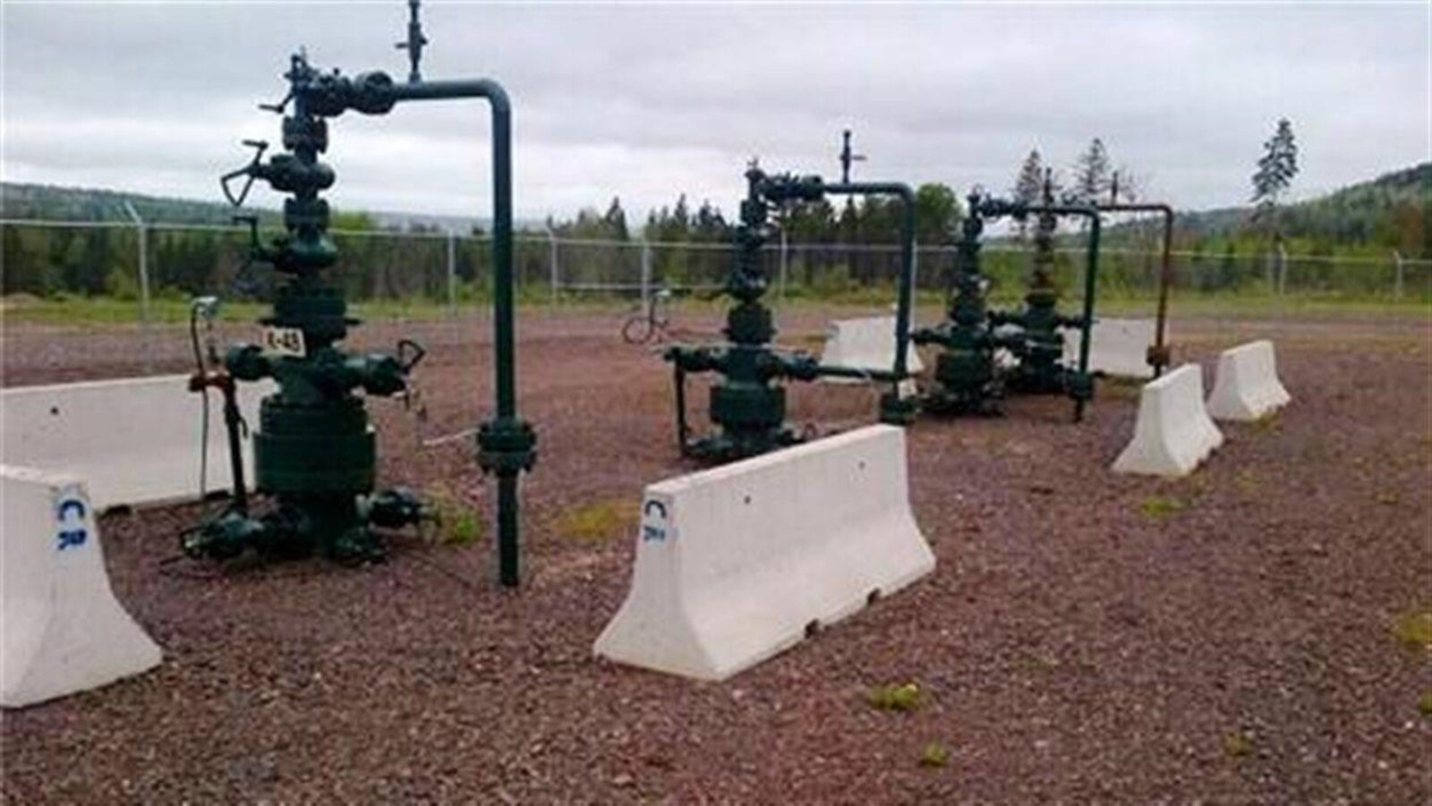 Tuyauterie et valves sortant du sol dans une zone clôturée