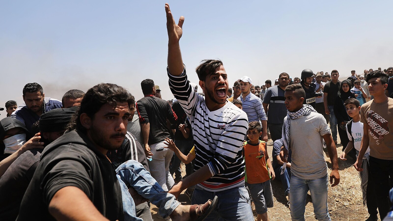 Des Palestiniens sont rassemblés à la barrière de sécurité israélienne; certains transportent des blessés.