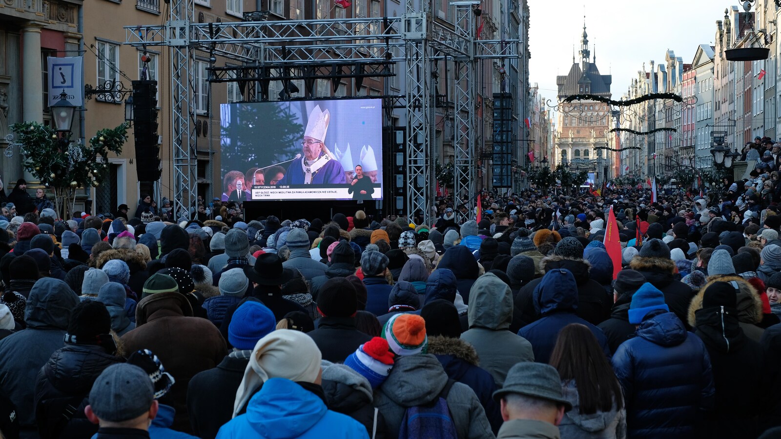 Une foule regarde un écran géant dans une rue.