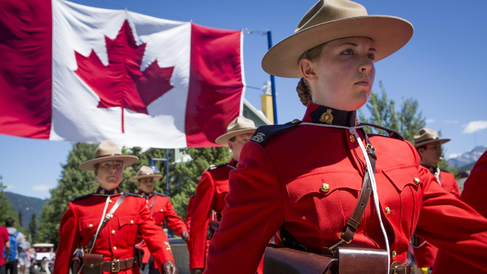 Des agents de la GRC portent un drapeau du Canada.