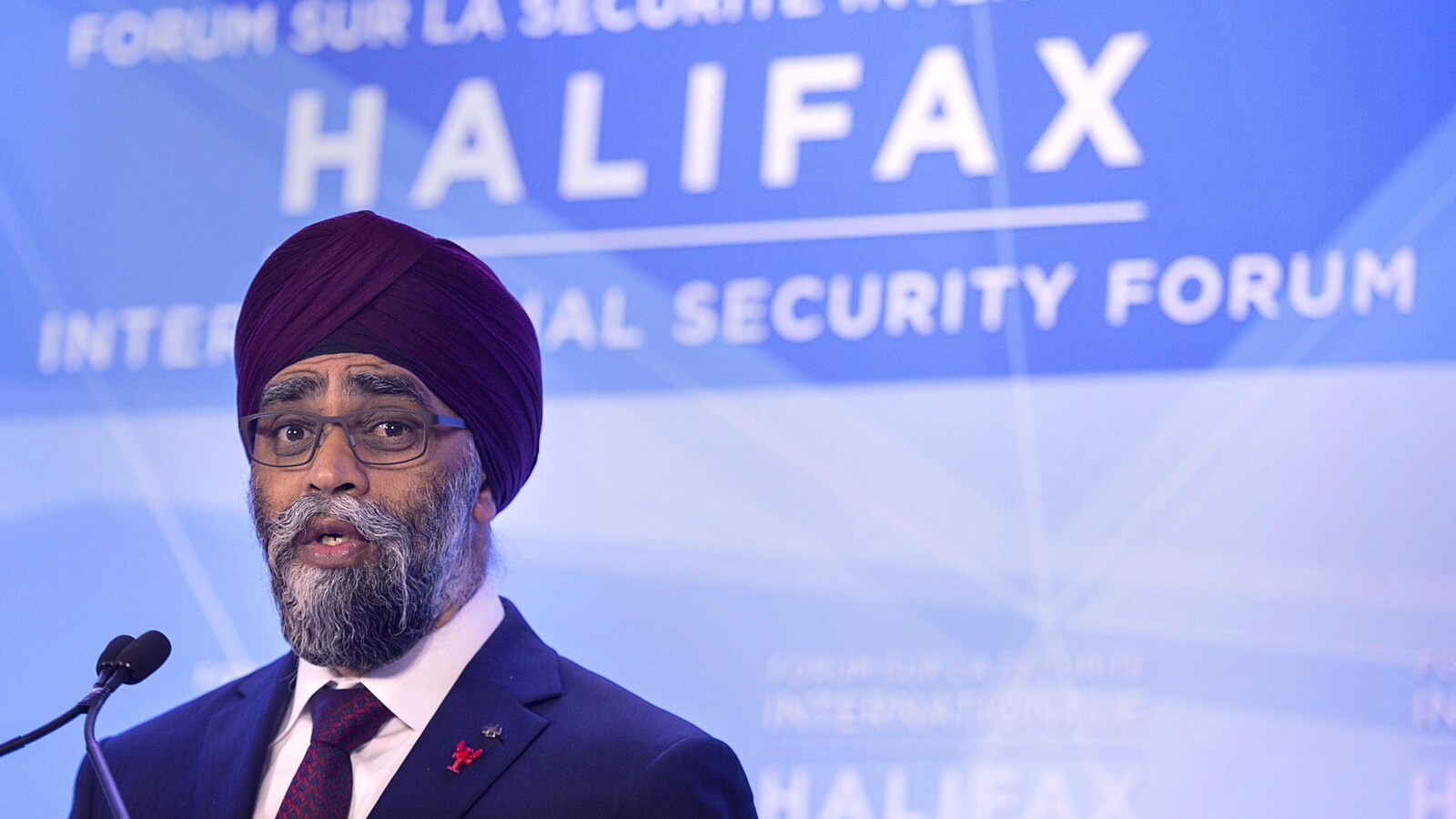 L'homme porte une barbe mi-longue et un turban de couleur bordeaux.