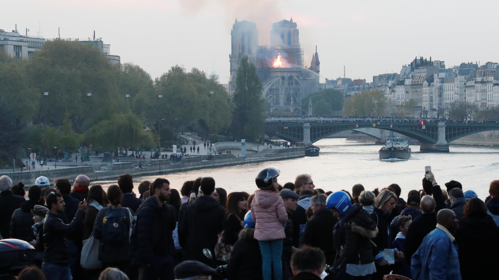 Des gens regardent la fumée s'échapper de la cathédrale Notre-Dame pendant l'incendie qui s'est déclaré le 15 avril 2019.