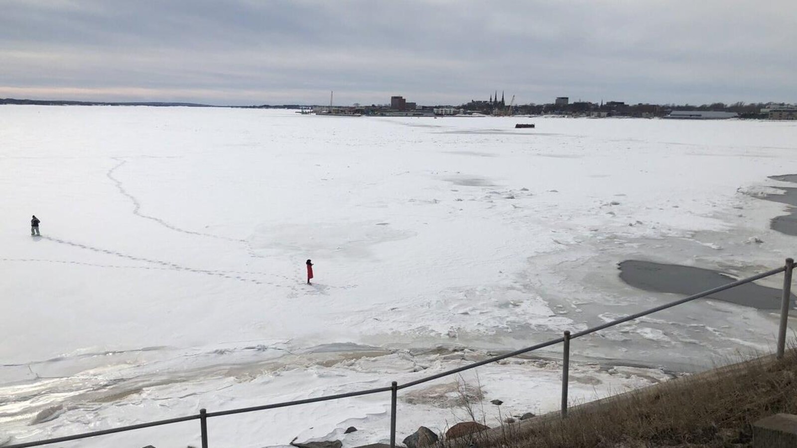 Deux personnes sur la glace avec le centre-ville de Charlottetown en arrière-plan.