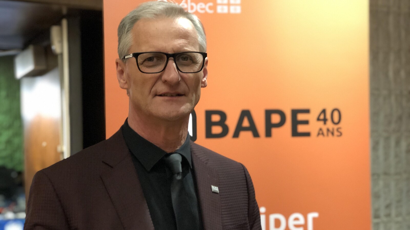 Gérald Savard devant une affiche du BAPE.