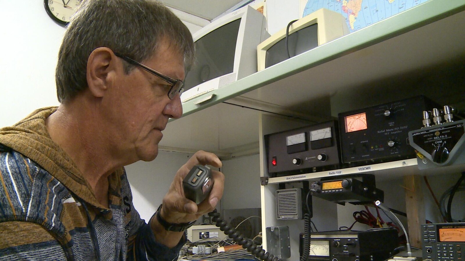 Un homme qui parle dans un microphone relié par un fil à des installations de radio amateur.