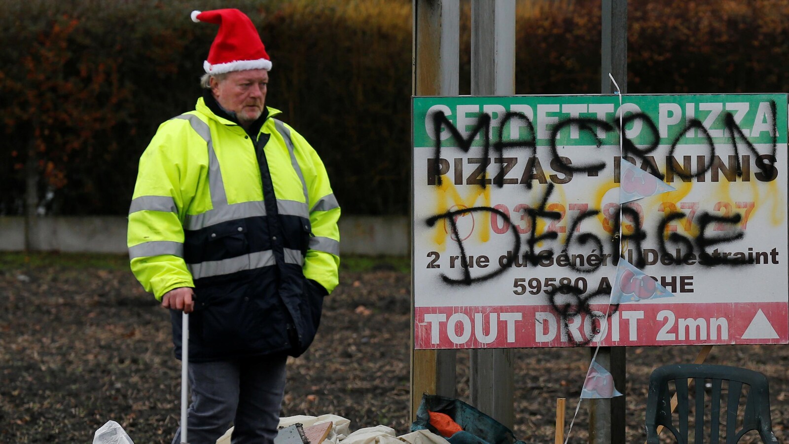 Un homme qui porte un gilet jaune se tient debout.