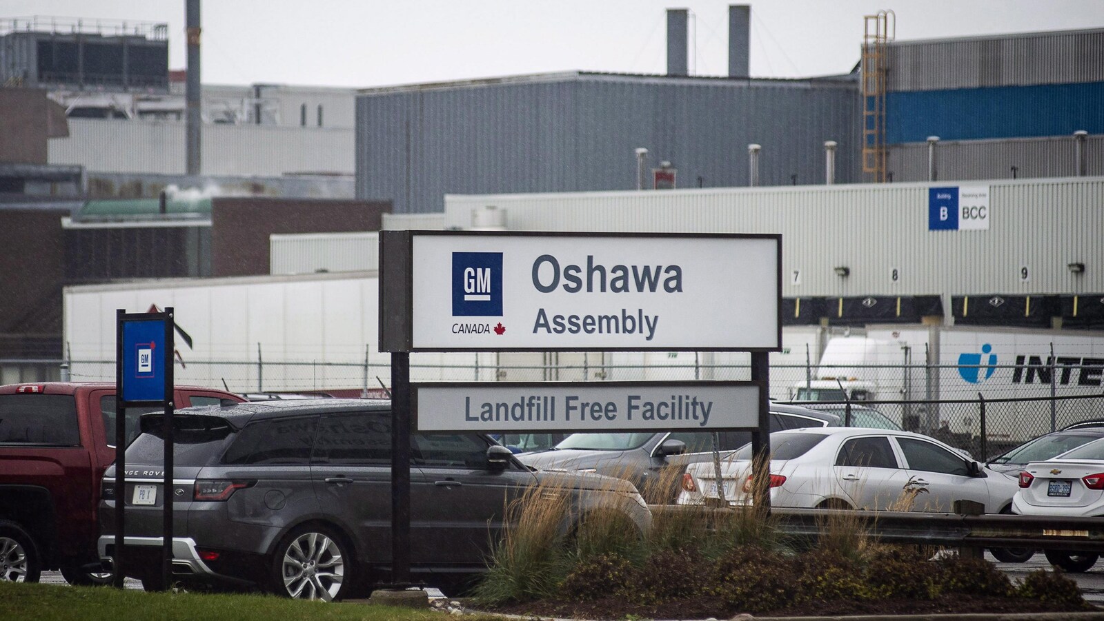 Des voitures devant une usine au loin.