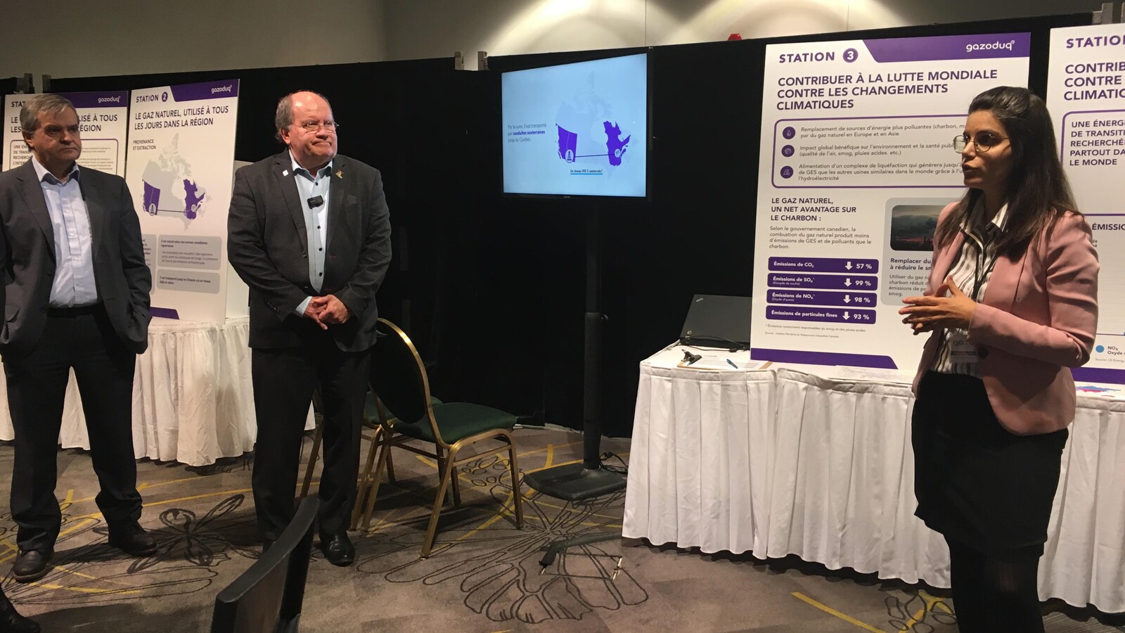 Une responsable de GNL Québec parle devant un groupe en utilisant des affiches et un écran.