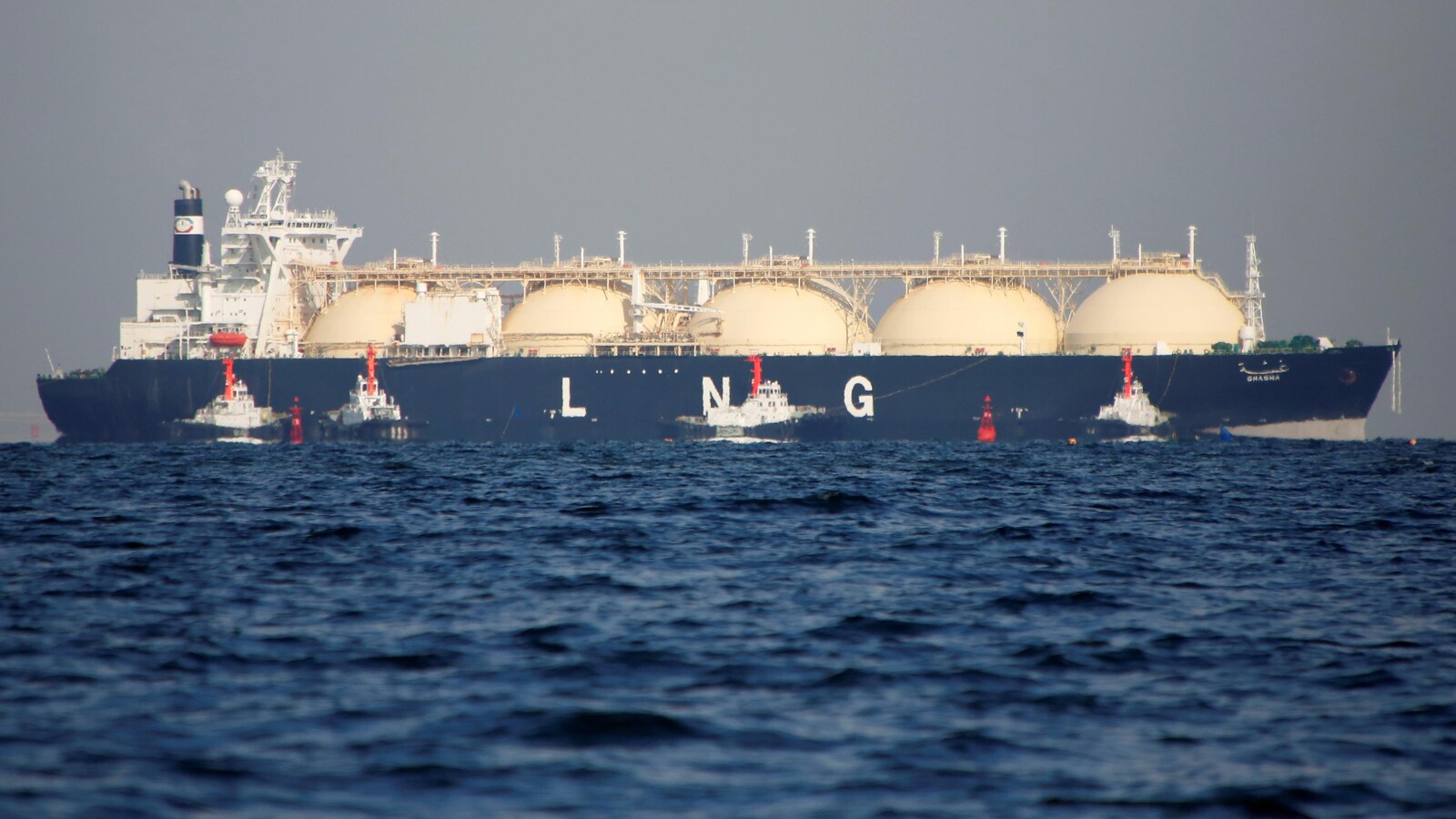 Des remorqueurs guident un navire de GNL sur une mer plate à l'est de Tokyo