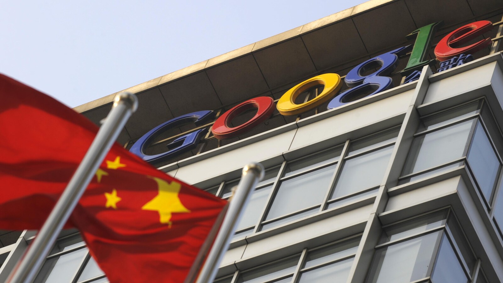 Un drapeau chinois flotte devant un bâtiment affichant le logo de Google.
