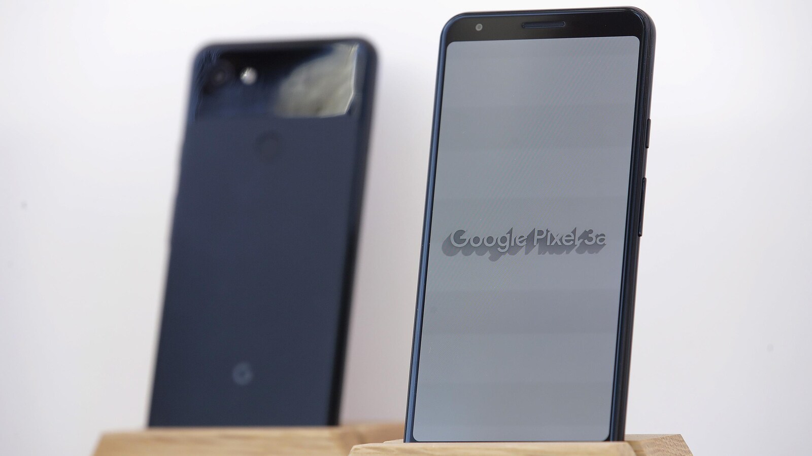 Une photo de deux téléphone Google Pixel 3a sur des présentoirs en bois.