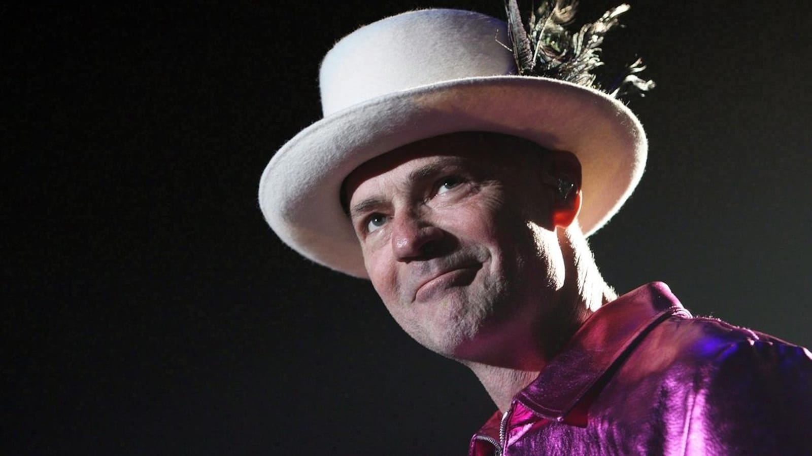 Le chanteur Gord Downie sourit en levant les yeux au ciel, son chapeau blanc sur la tête.