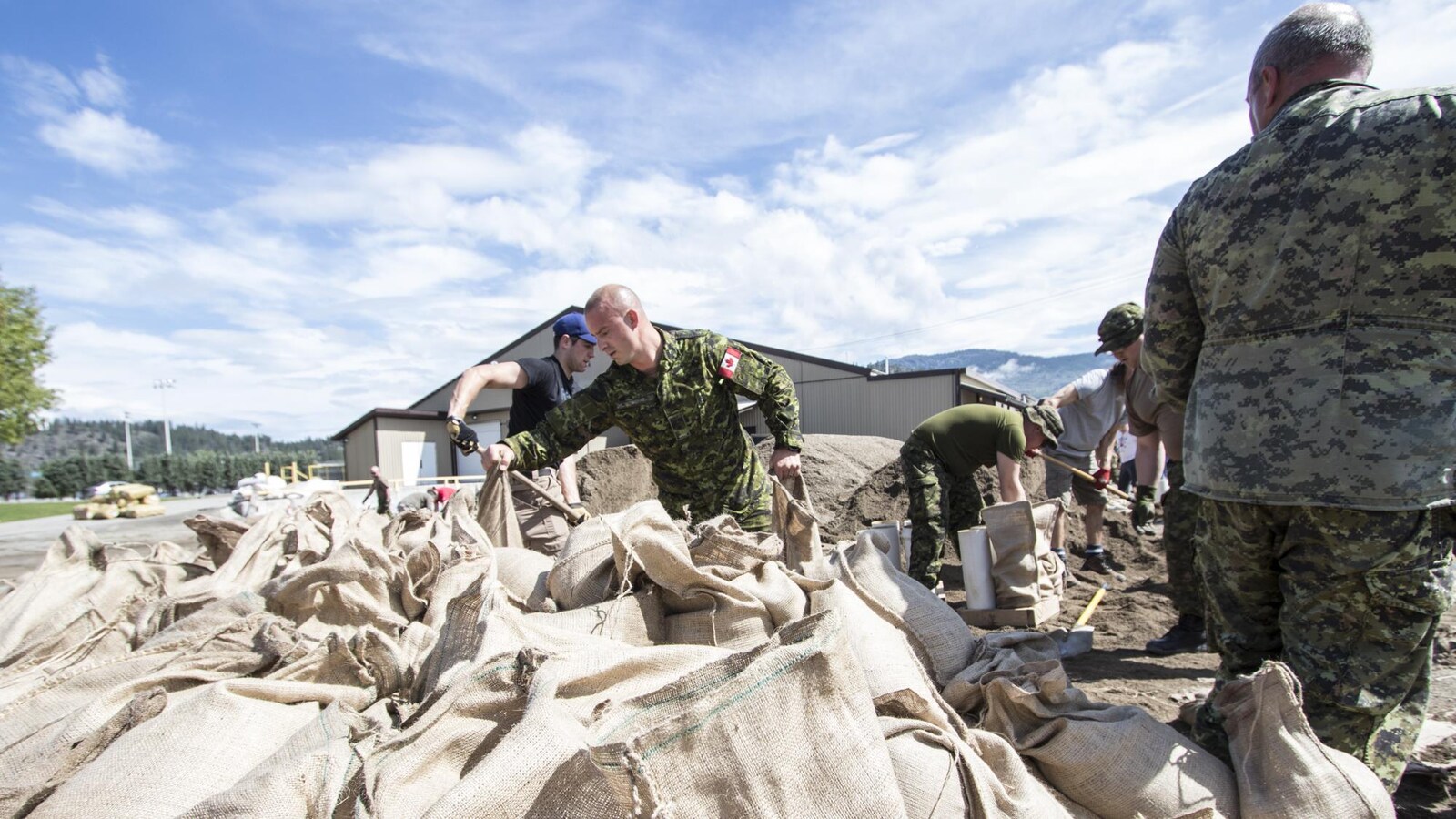 Des militaires remplissent des sacs de sable pour protéger la ville de Grand Forks en Colombie-Britannique, dont le centre-ville est inondé depuis une semaine.