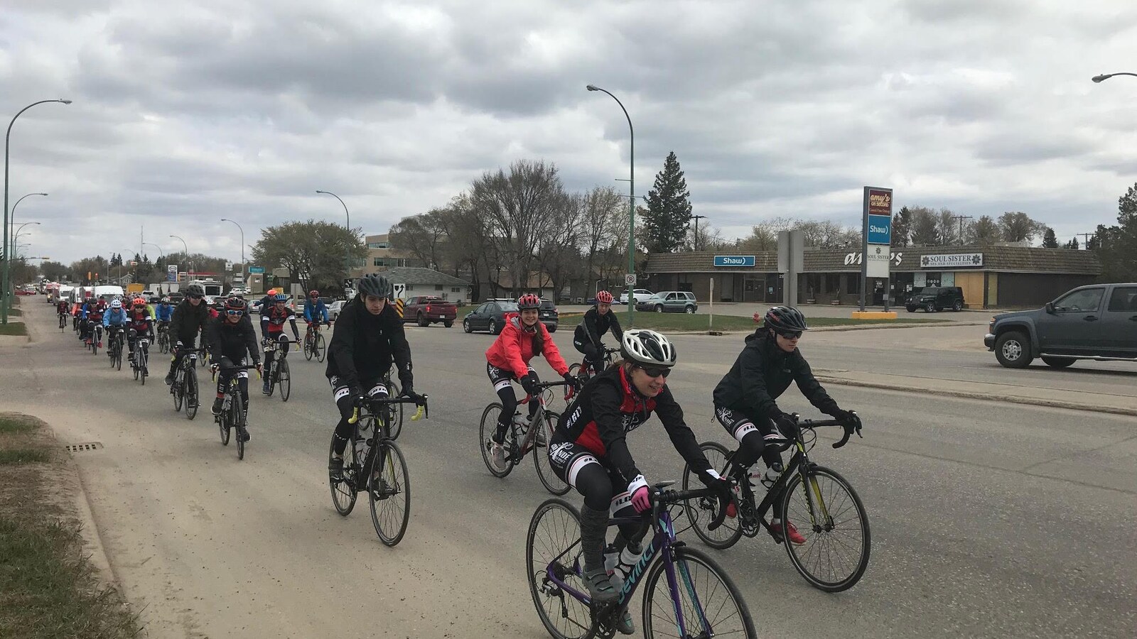 Plus d'une dizaine de cyclistes sont assis sur leurs vélos et pédalent.