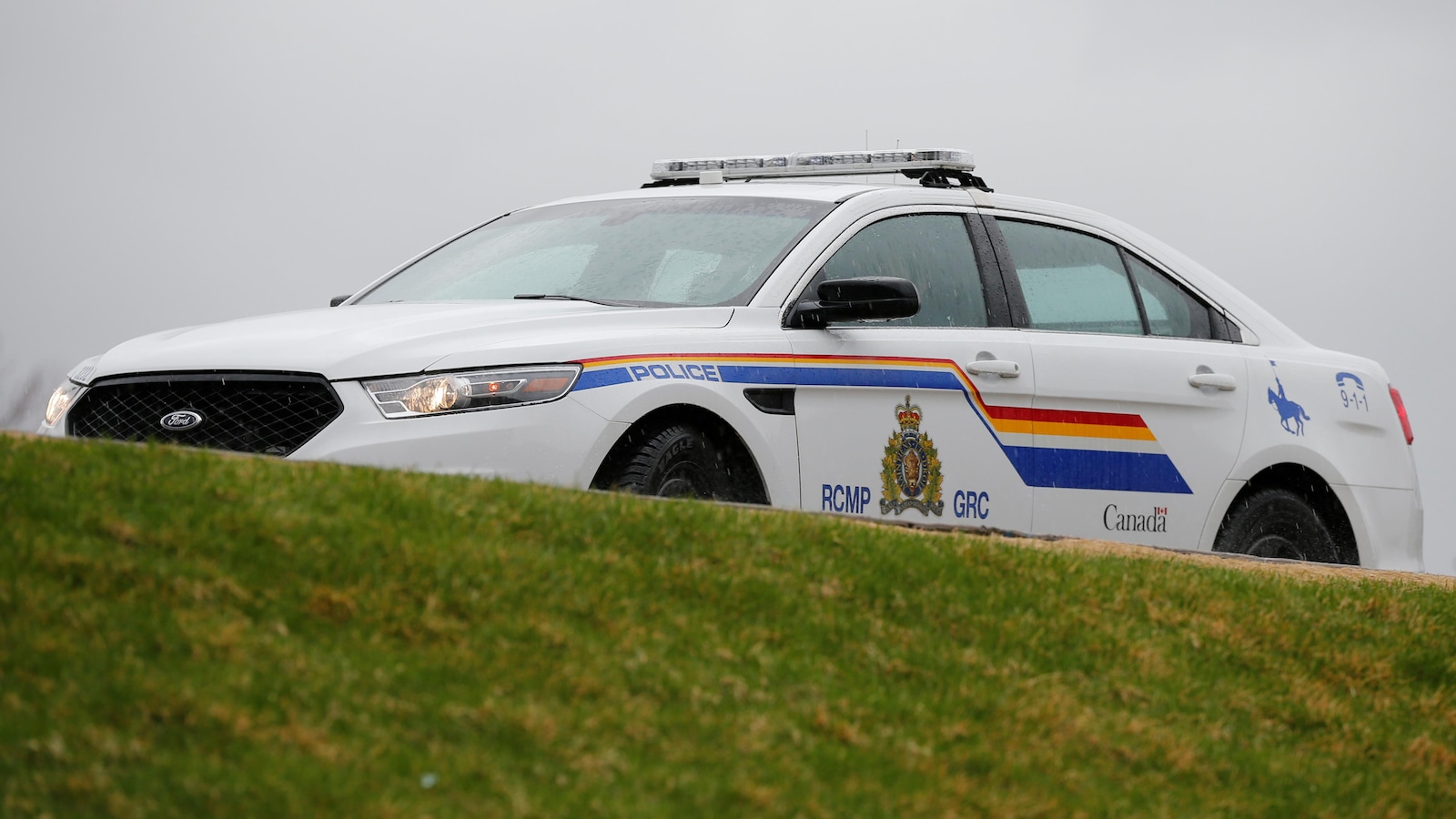 Une voiture peinte aux couleurs de la Gendarmerie royale du Canada passe sur un talus.