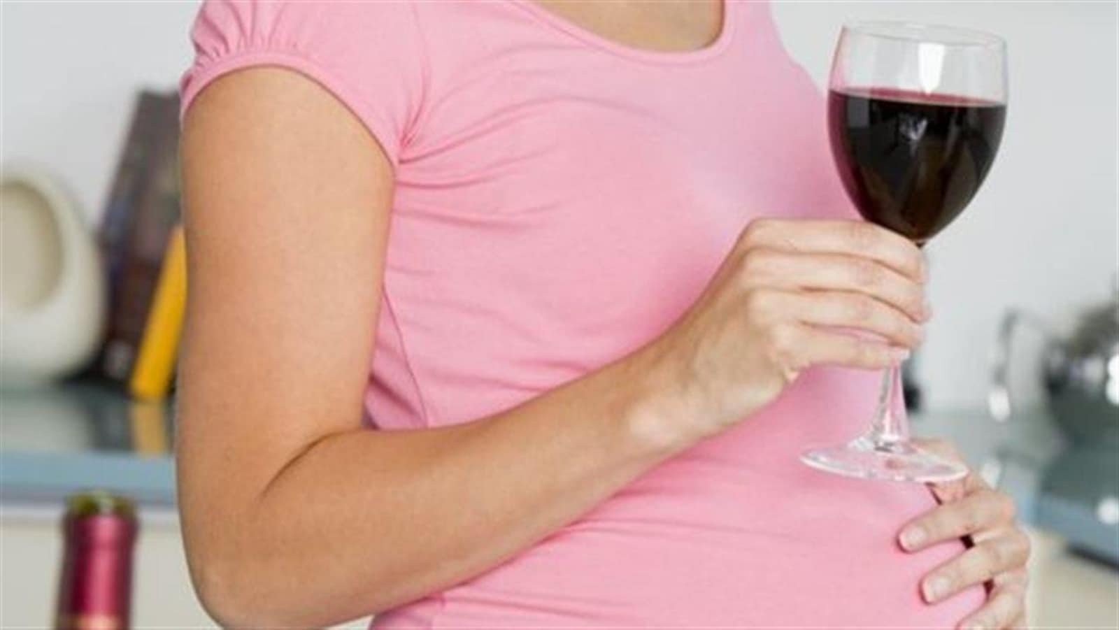 Une femme enceinte, un verre de vin rouge à la main