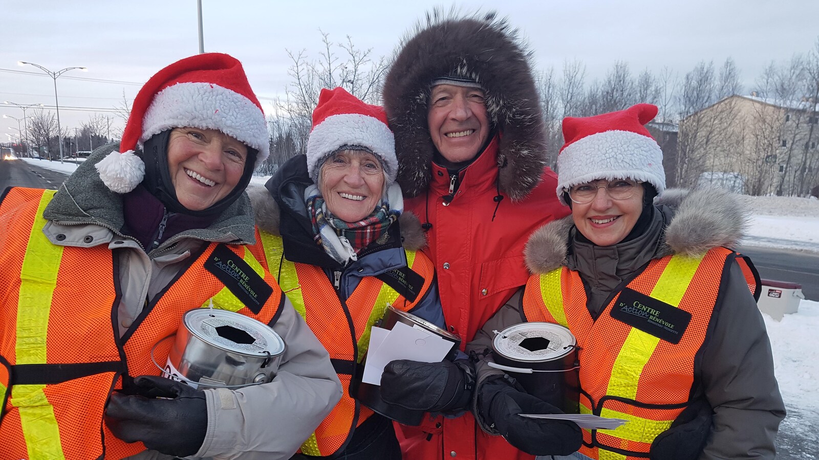 Quatre bénévoles de Rimouski chaudement habillés avec leur pot de récoltes à leurs mains.