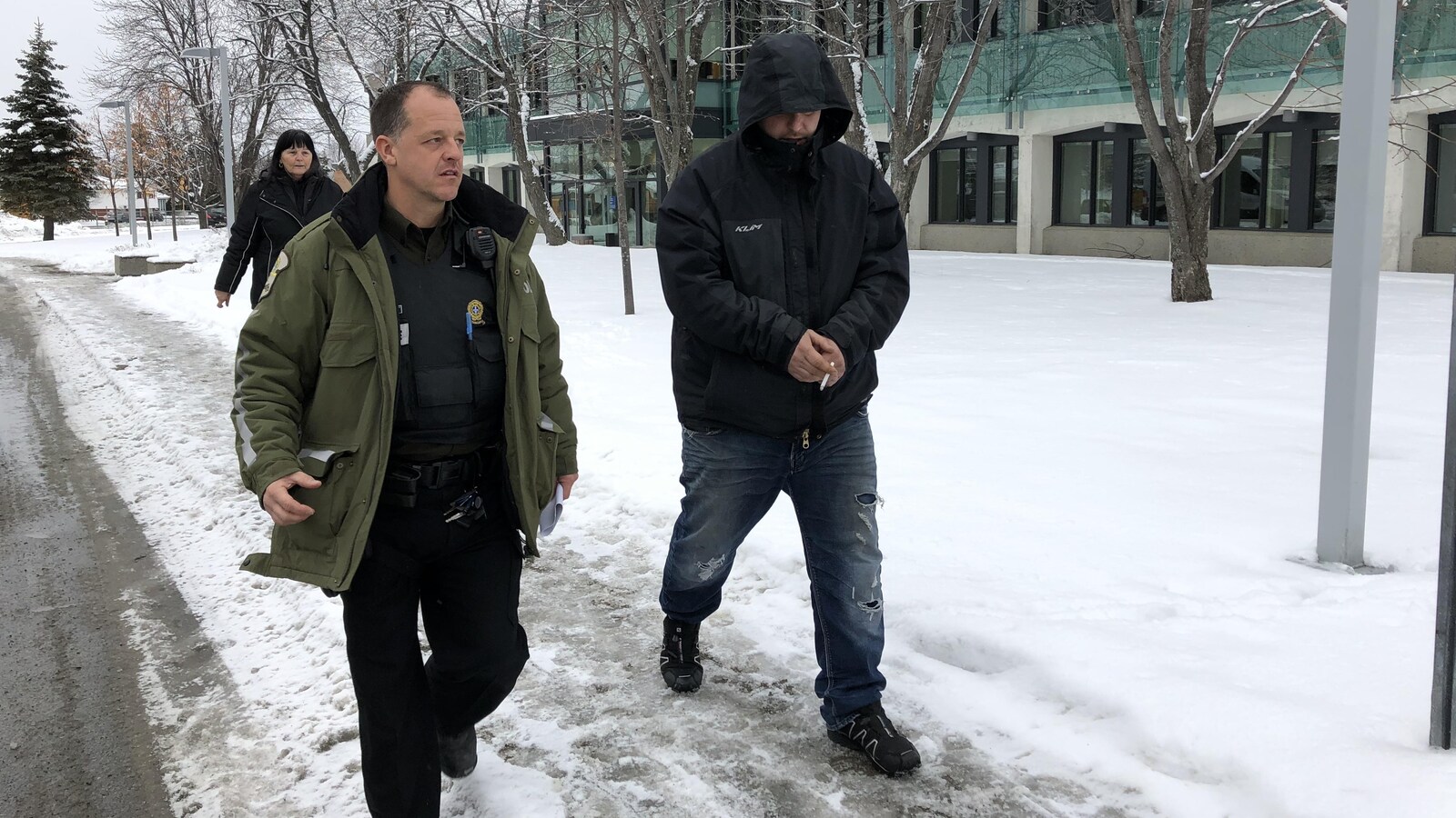 Un accusé est escorté par un policier au palais de justice de Val-d'Or.