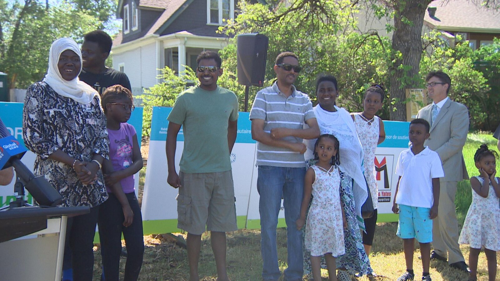 Des familles et leurs enfants sourient sur la pelouse d'un quartier résidentiel.