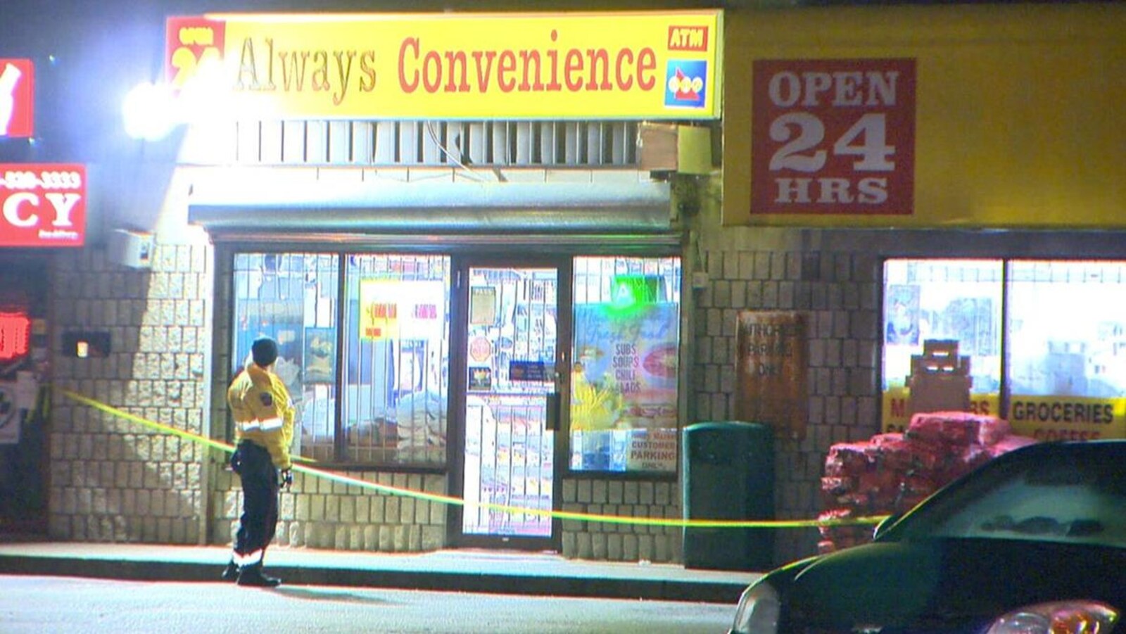 Photo de l'enseigne jaune du dépanneur; un policier monte la garde devant l'édifice.
