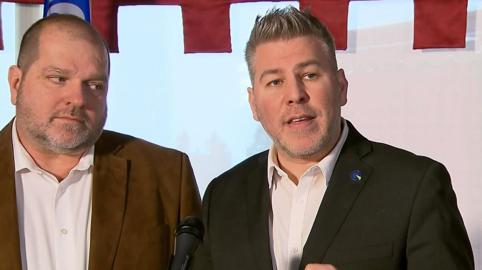 Deux hommes répondent aux questions des médias en conférence de presse.