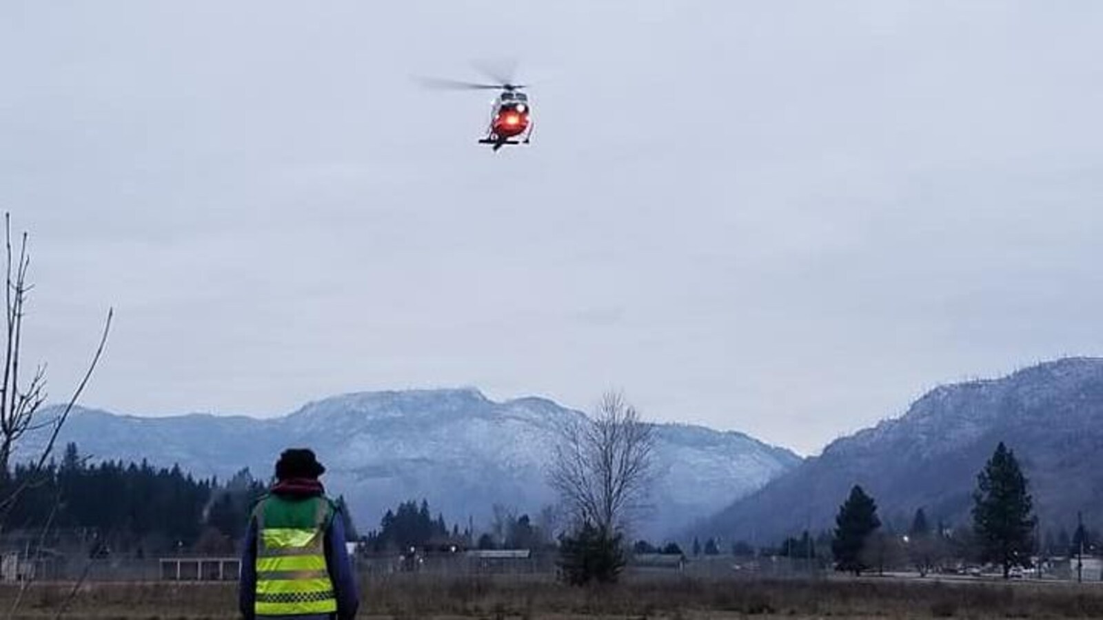 Un hélicoptère du Service des ambulanciers de la Colombie-Britannique survole un paysage montagneux