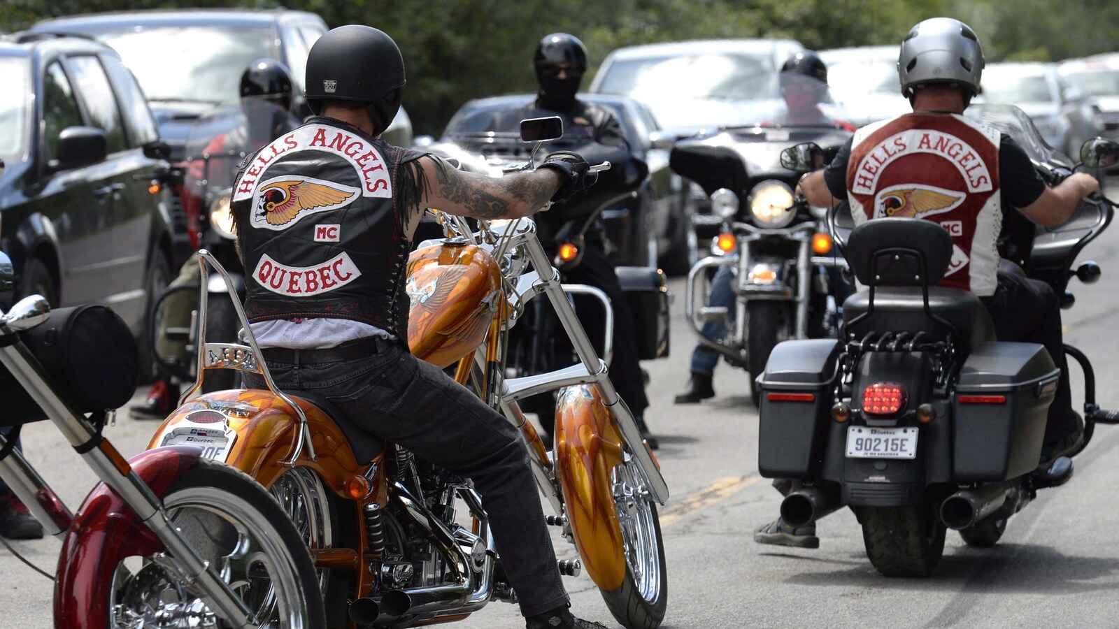 Un homme est sur sa moto avec une veste arborant une tête de mort ailée, symbole des Hells Angels.