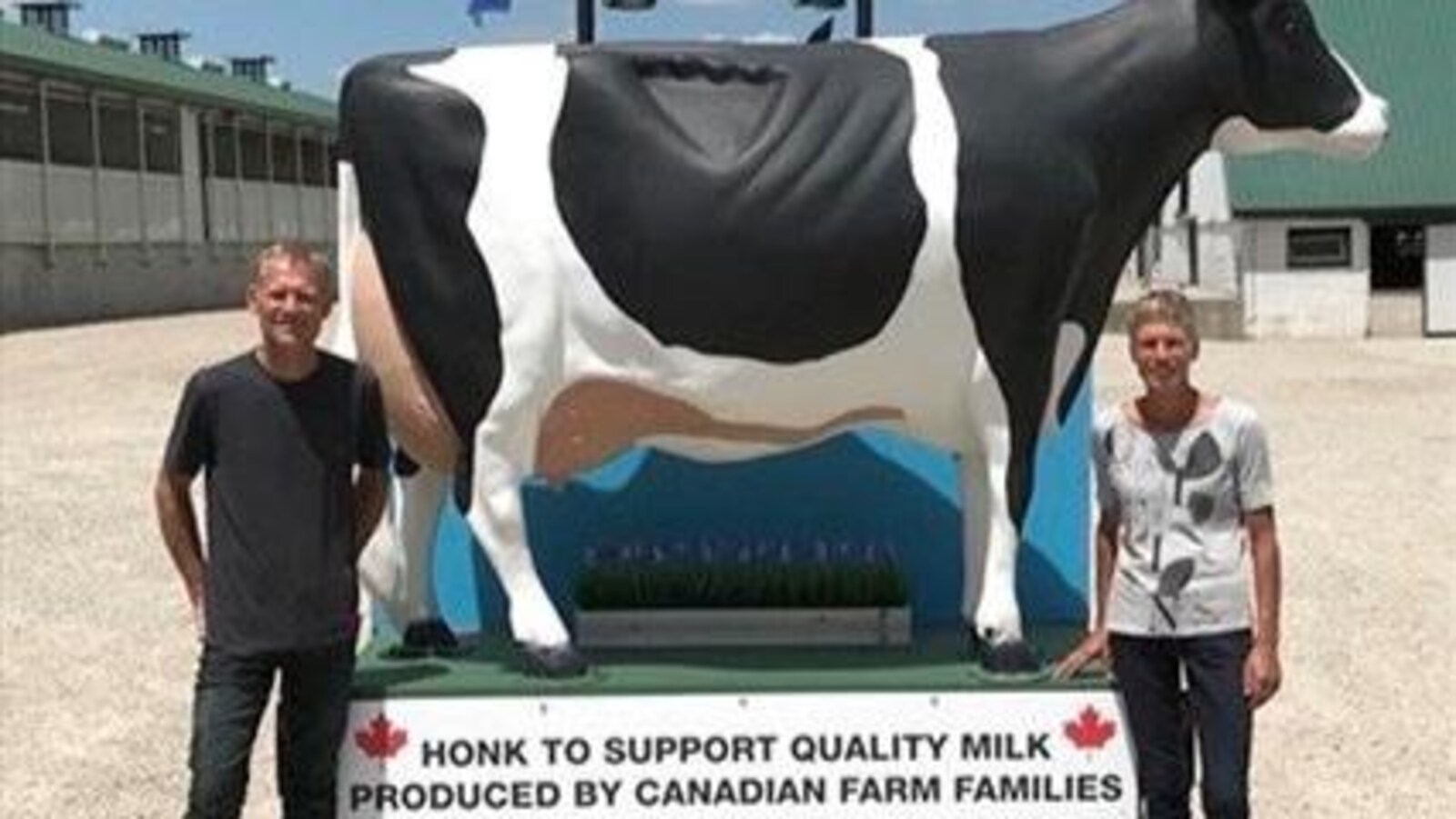 Photo d'un homme et d'une femme en t-shirt qui se tiennent devant une énorme vache en plastique.