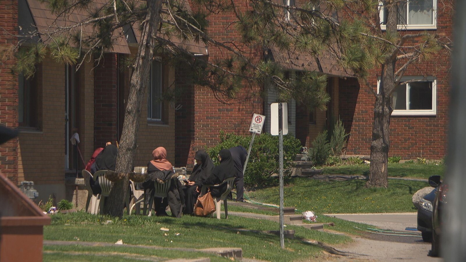 Des femmes voilées discutent, assises à l'extérieur devant des logements en briques. (Archives)