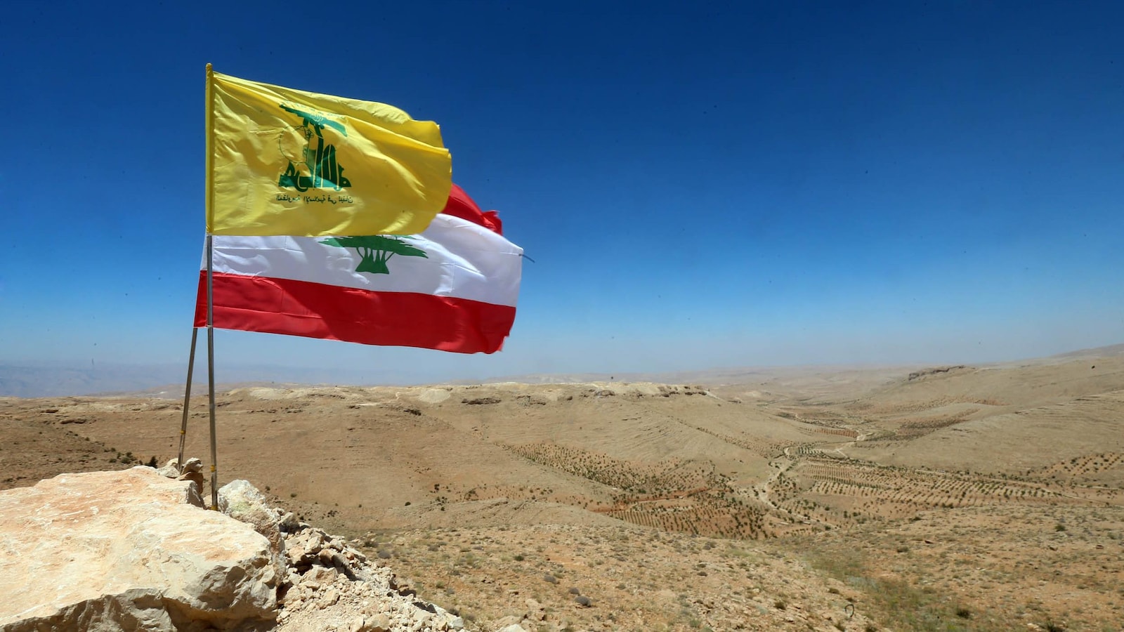 Le drapeau du Liban et celui du Hezbollah flottant au-dessus d'une vallée désertique dans la ville d'Ersal, dans le nord du Liban. 
