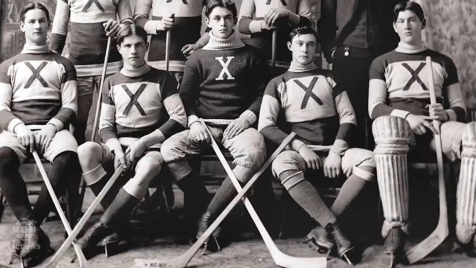 Photo en noir et blanc de cinq joueurs de hockey qui posent avec leur bâton à la main.