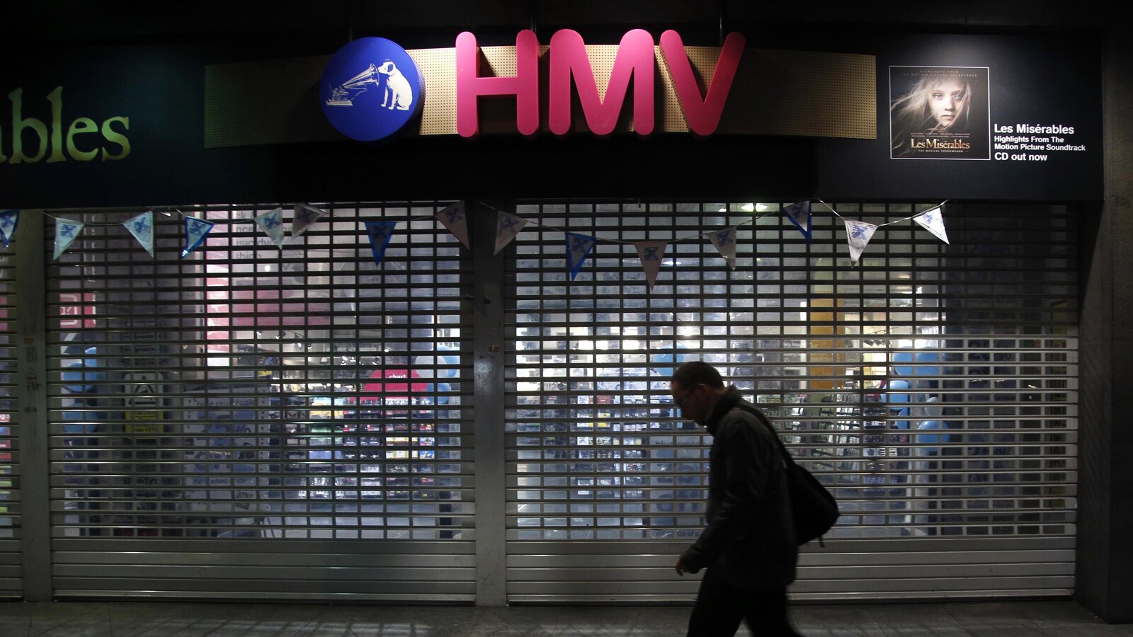 Un homme marche devant une succursale fermée du disquaire HMV.