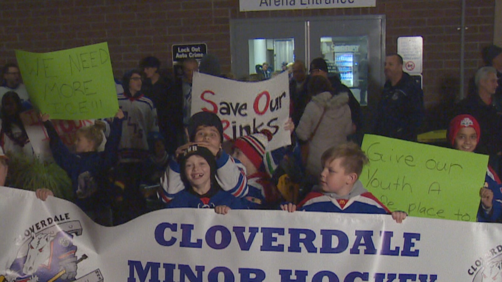 Des enfants souriants et portant des chandails de hockey tiennent une bannière portant le nom de l'association de hockey pour enfants de Cloverdale.