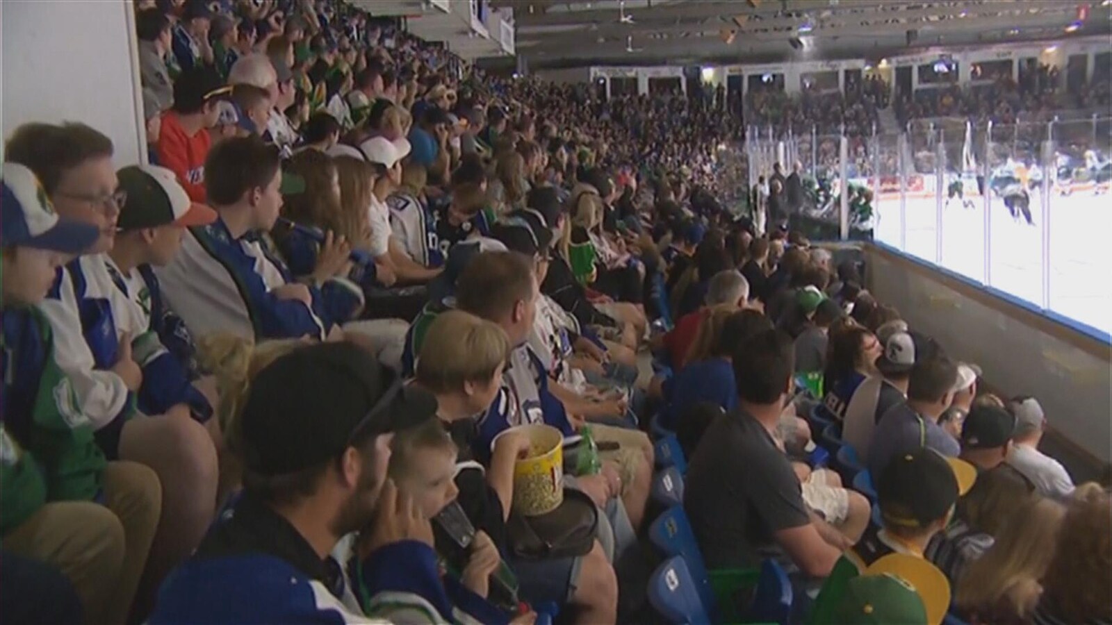 La foule porte des chandails de hockey et regarde attentivement la glace où se déroule le match.